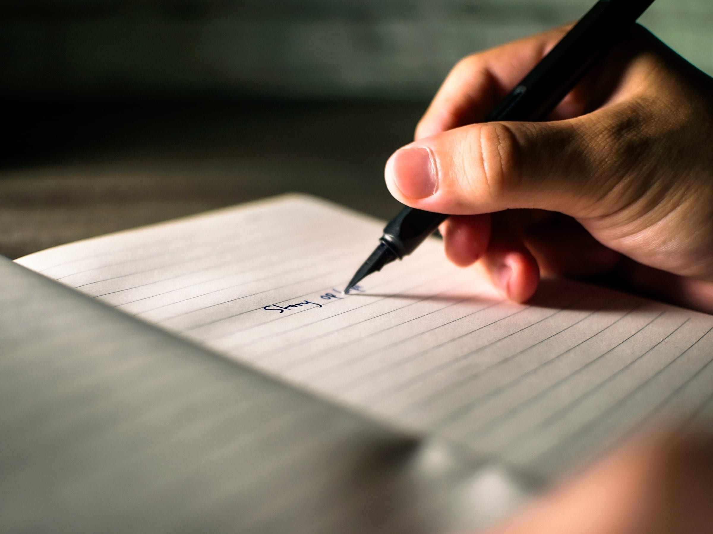 Editorial photograph — a hand writing with a fountain pen on fine paper
