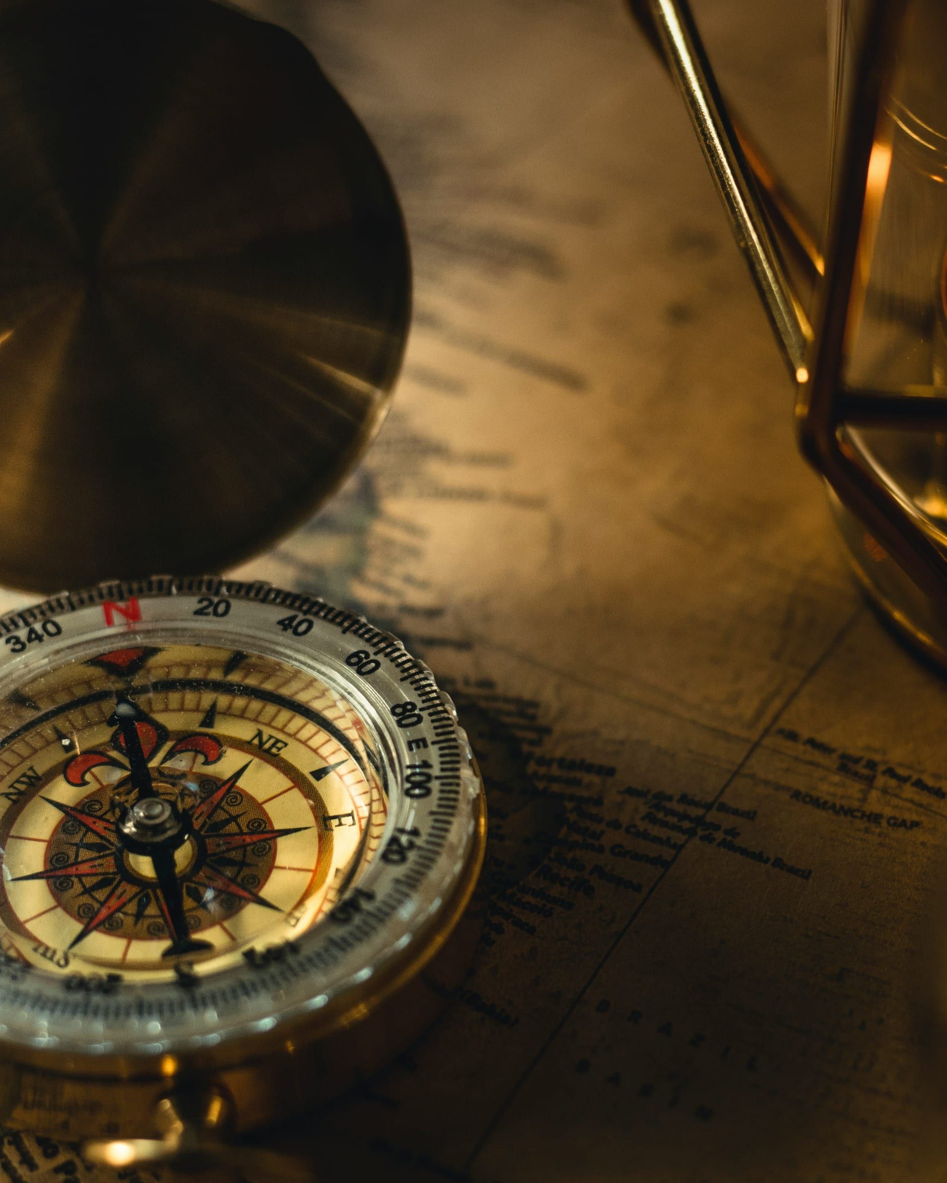 Editorial photograph — an old world map with a brass compass in golden-hour light